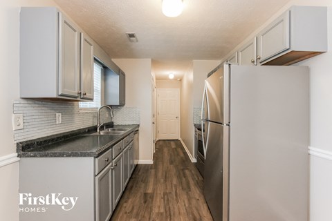 A kitchen with a refrigerator, sink, and cabinets.