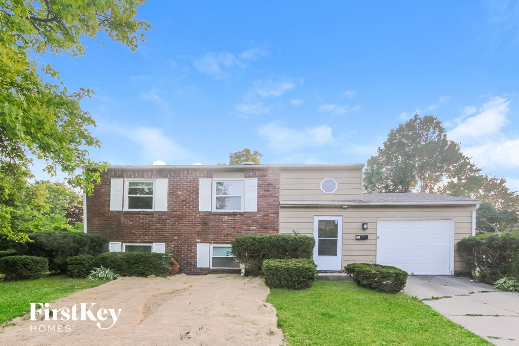 a brick house with a white garage door and a lawn