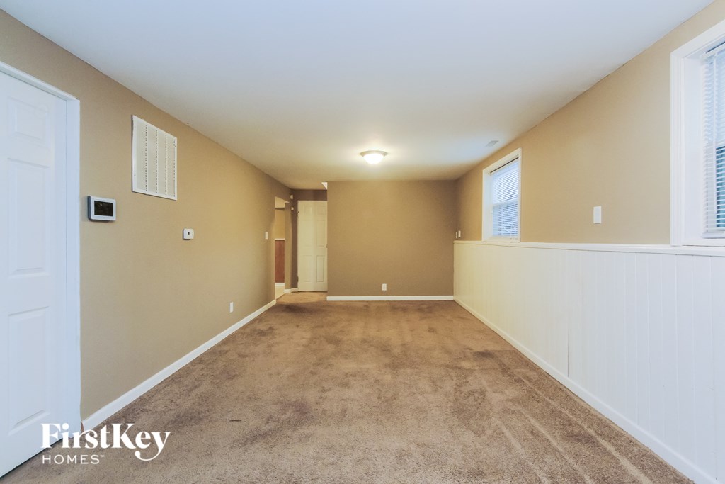 a spacious living room with beige walls and carpet and a white door and window