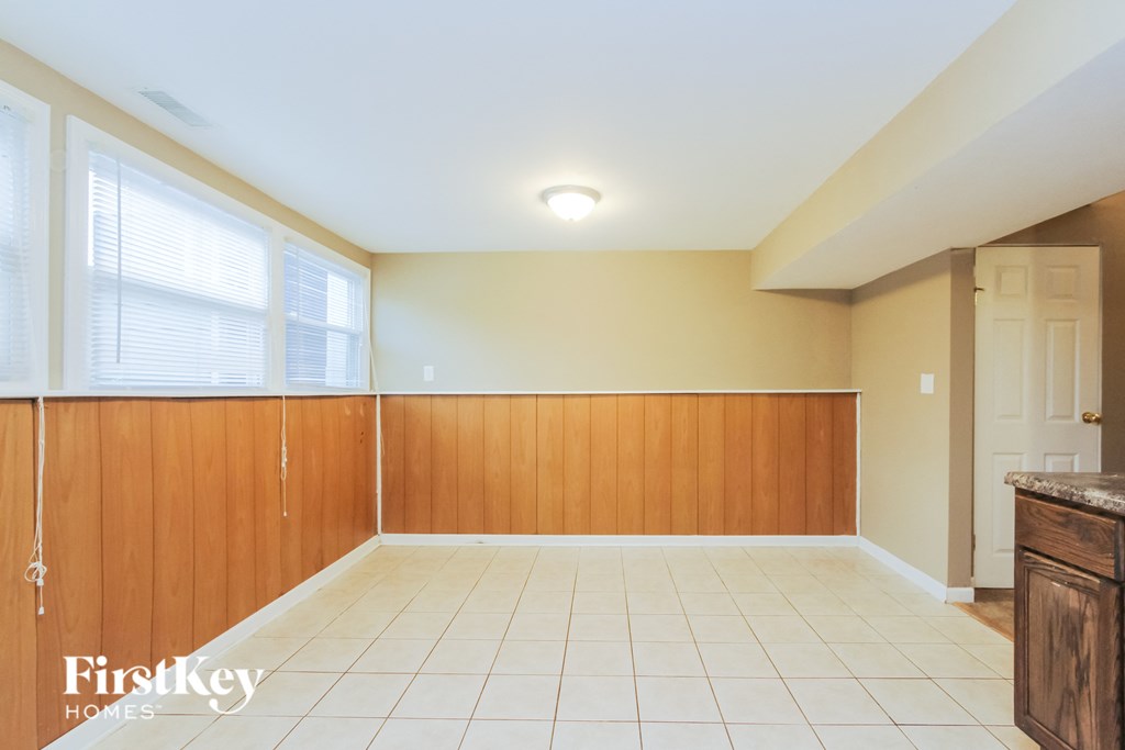 an empty dining room with wood paneling and a white tile floor