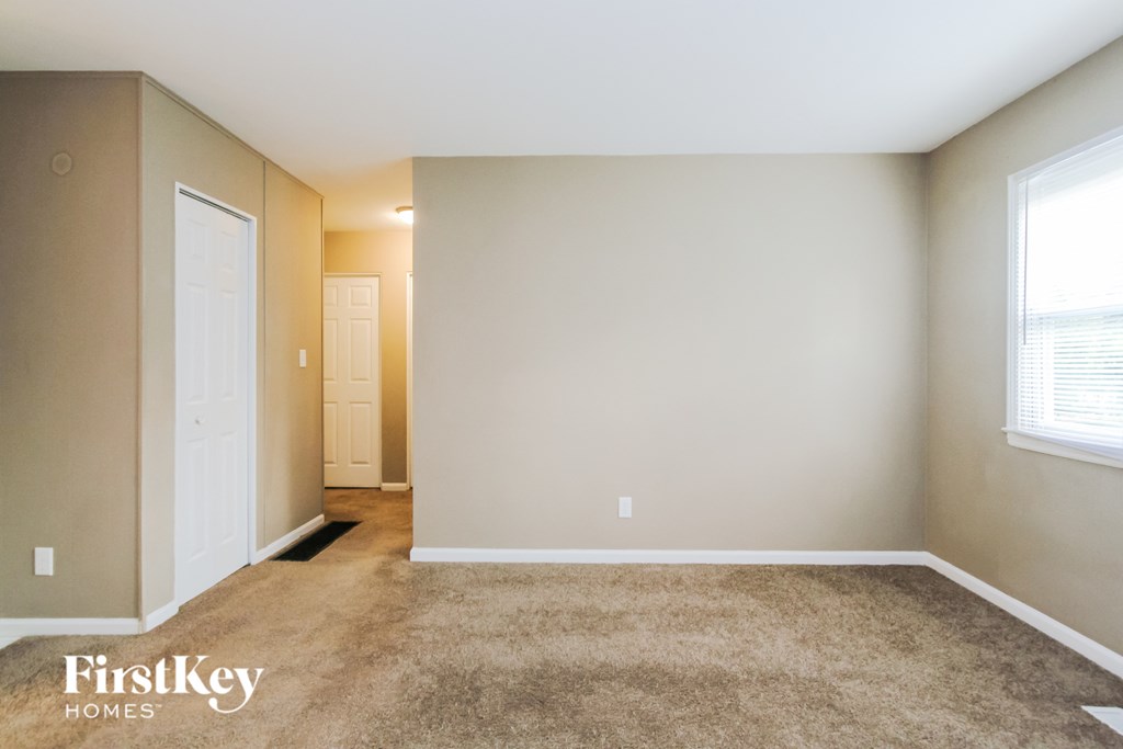 a room with a carpeted floor and a white door and a window