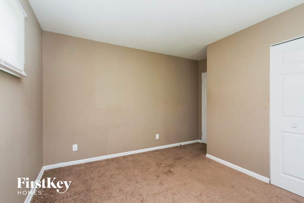 a bedroom with beige carpet and a white door