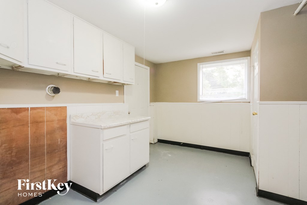 a kitchen with white cabinets and white appliances and a window