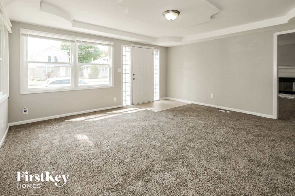 an empty living room with carpet and a fireplace