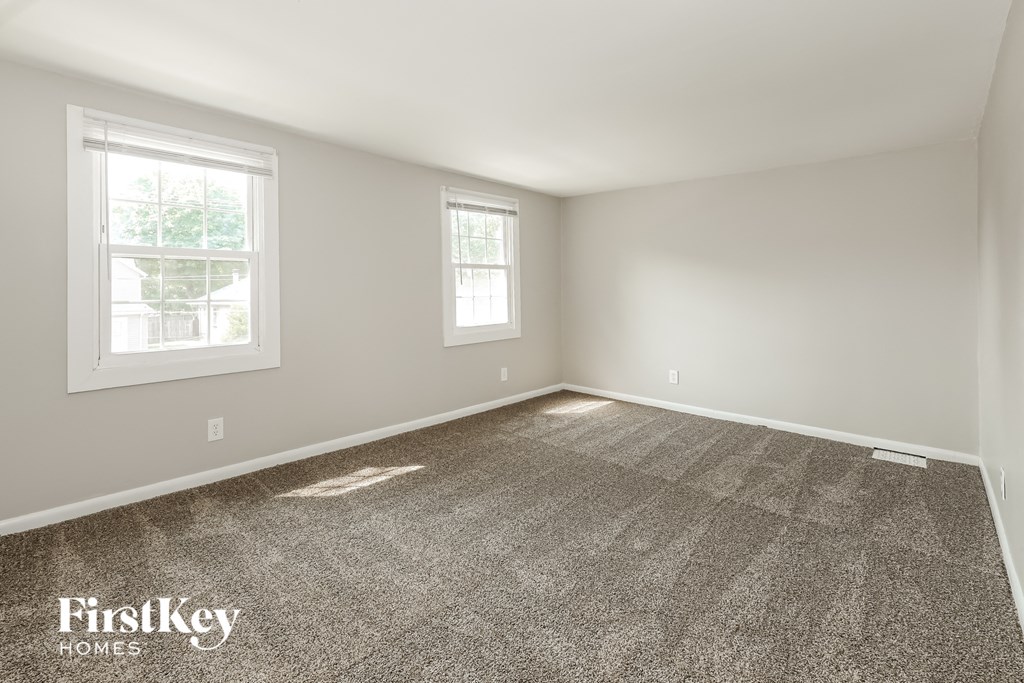 a empty room with carpet and two windows