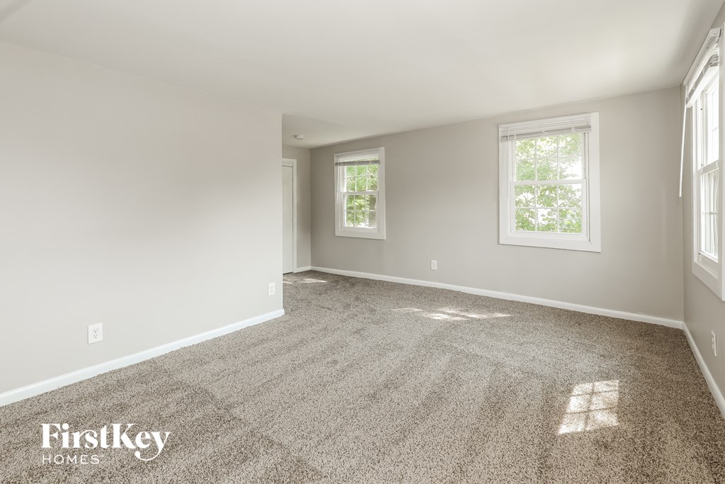 a empty living room with carpet and two windows