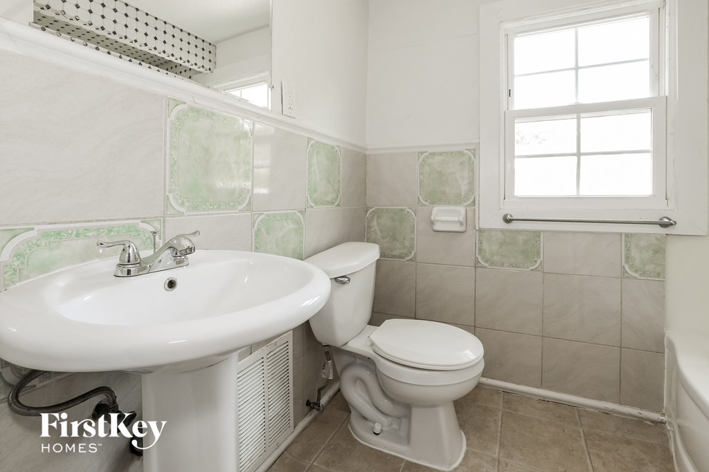 a white bathroom with a sink toilet and a window