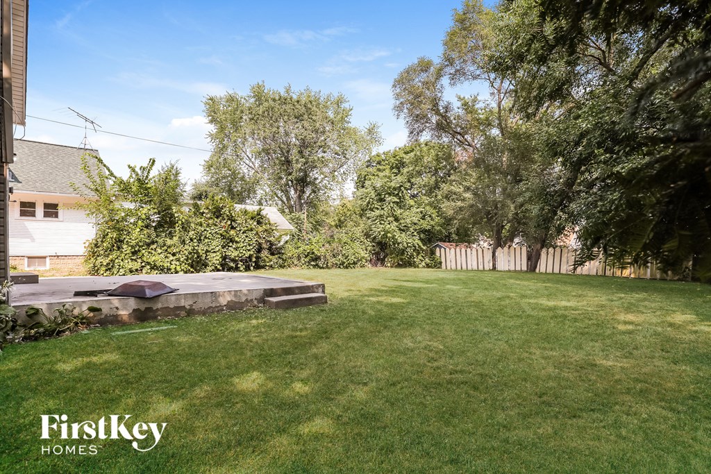 a backyard with a grass lawn and a stone fire pit