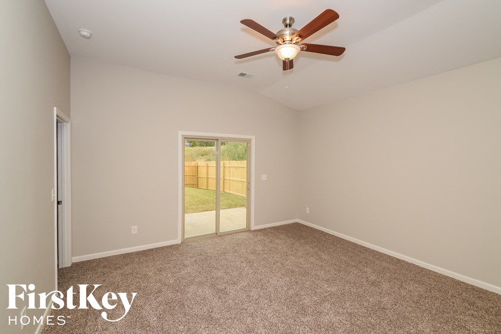 A room with a ceiling fan and a sliding glass door leading to a backyard.