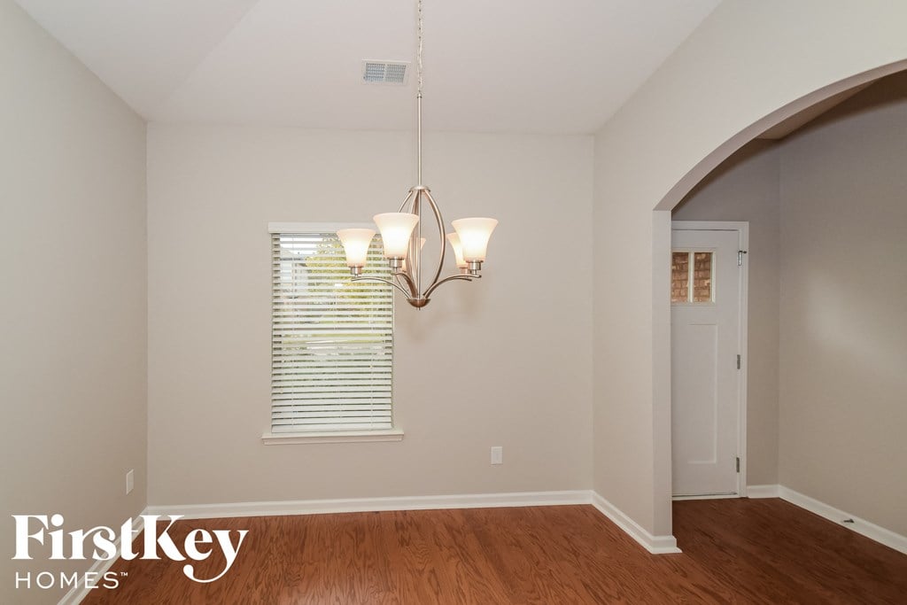 A room with a chandelier and a window with blinds.