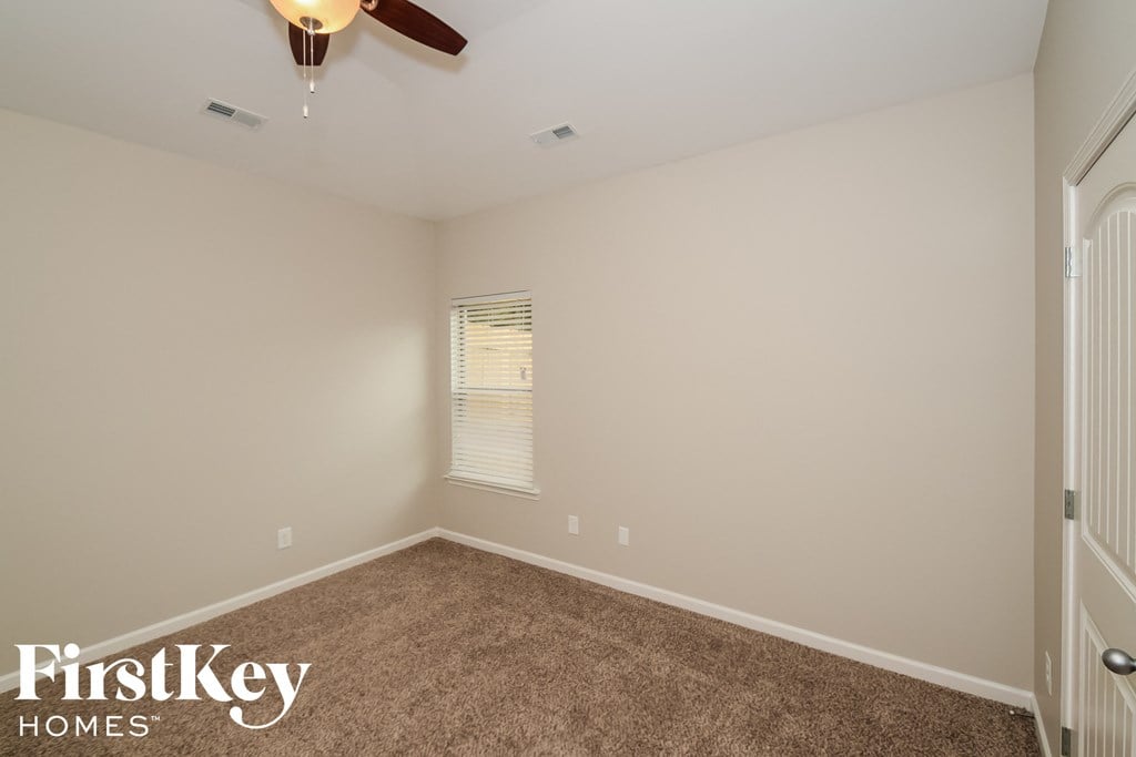 A room with a carpeted floor and a ceiling fan.