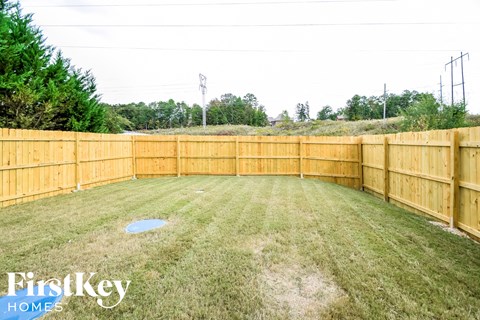 A backyard with a wooden fence and a grassy area.
