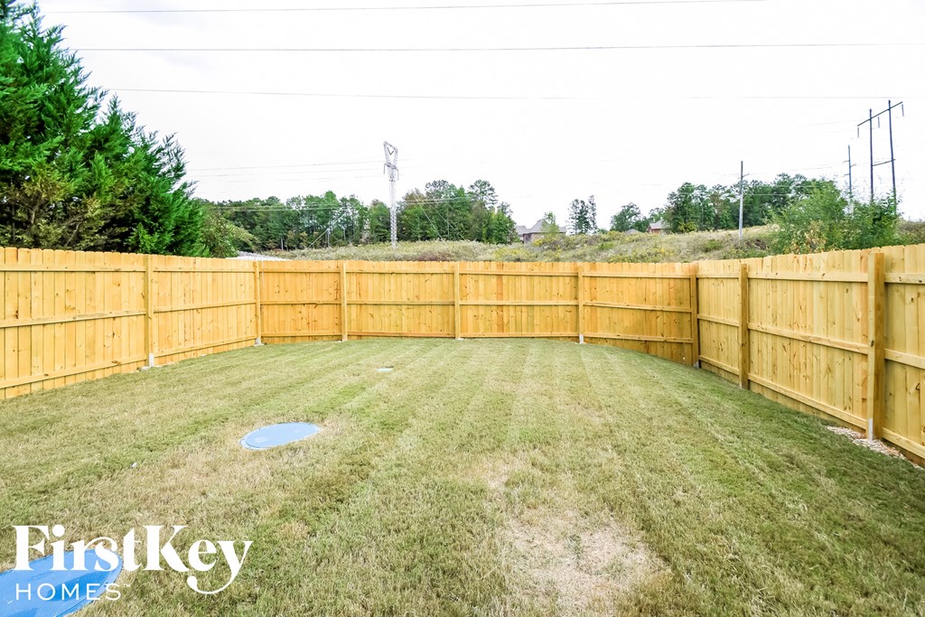 A backyard with a wooden fence and a grassy area.