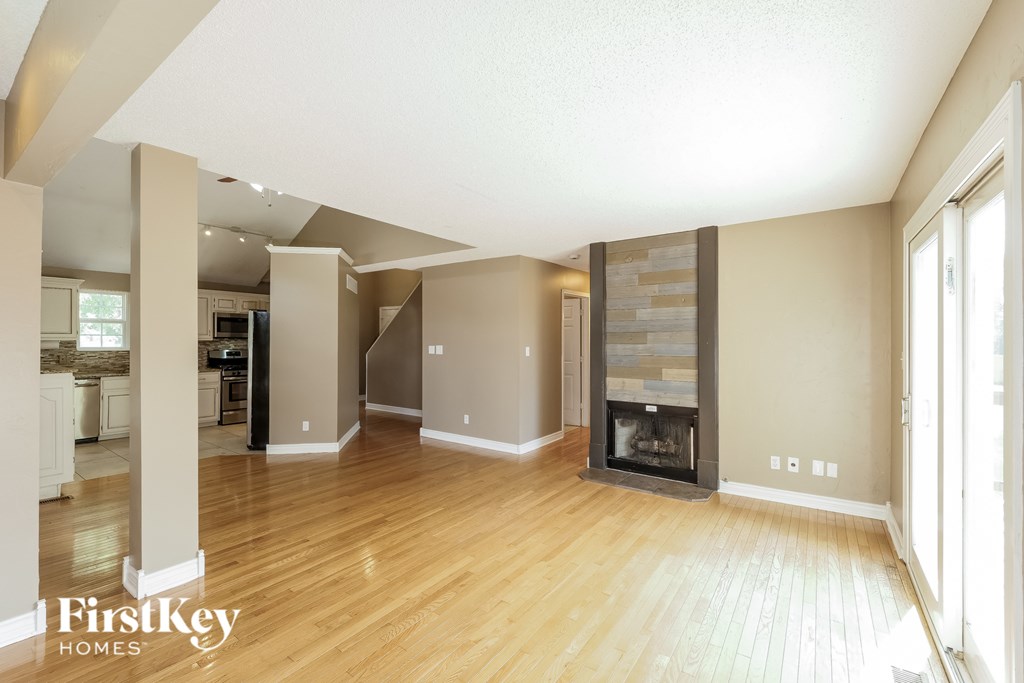 A spacious living room with wooden floors and a fireplace.