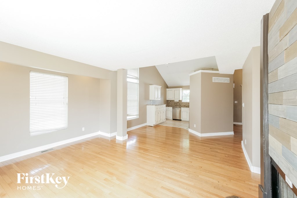 A spacious room with wooden floors and a large window.