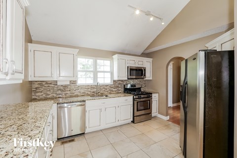 A kitchen with a refrigerator on the right side.