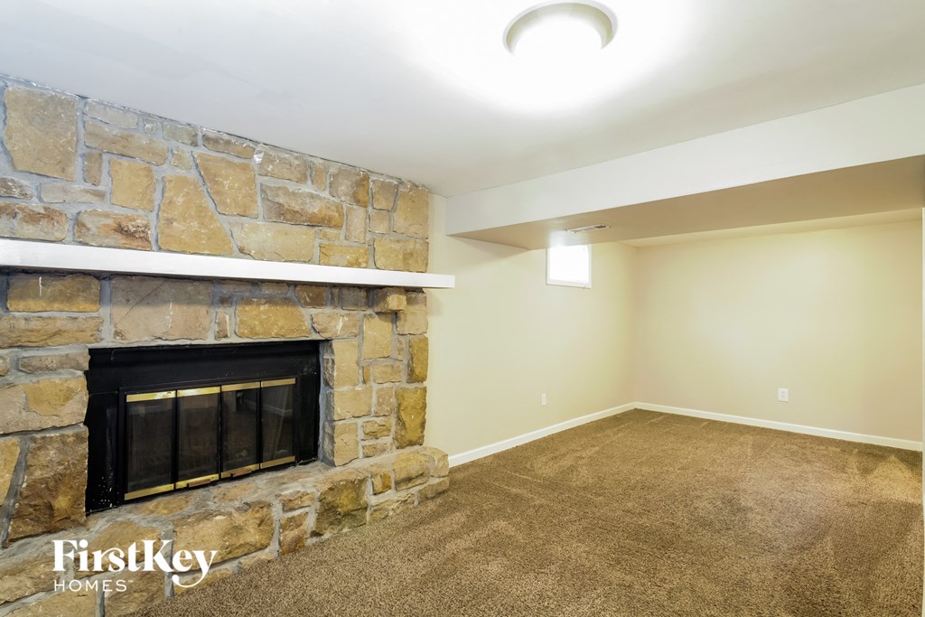 A stone fireplace in a room with a carpet floor.