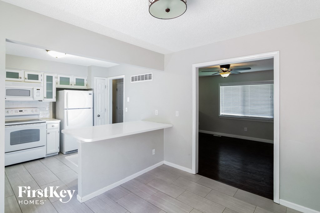 A kitchen with a refrigerator, microwave, oven, and sink.
