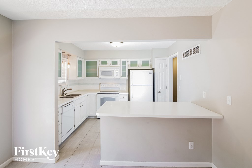 A kitchen with white cabinets and appliances.