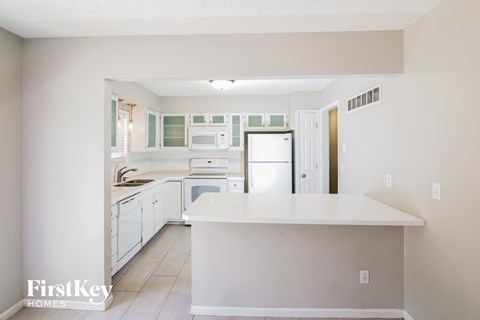 A kitchen with white cabinets and appliances.