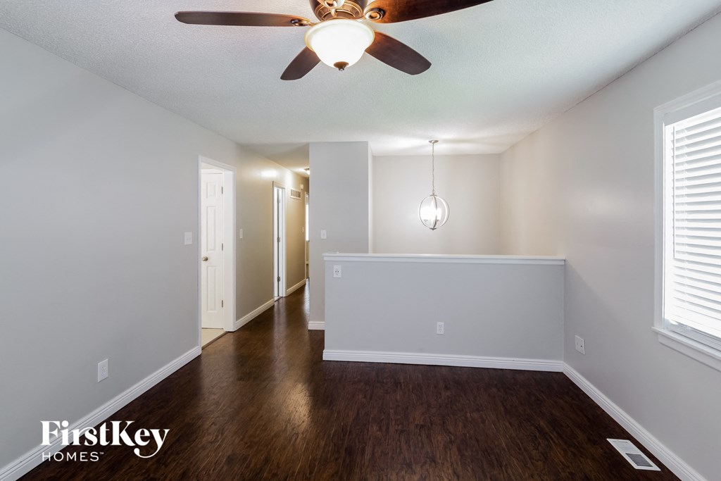 A spacious room with a ceiling fan and hardwood floors.