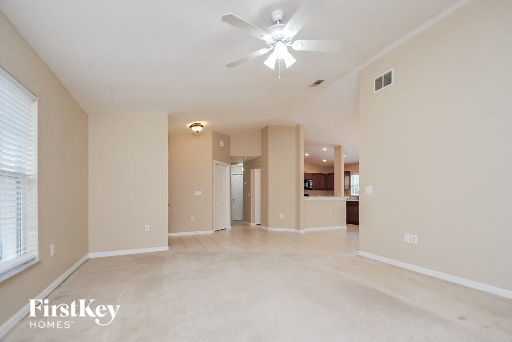 a spacious living room with beige walls and a ceiling fan
