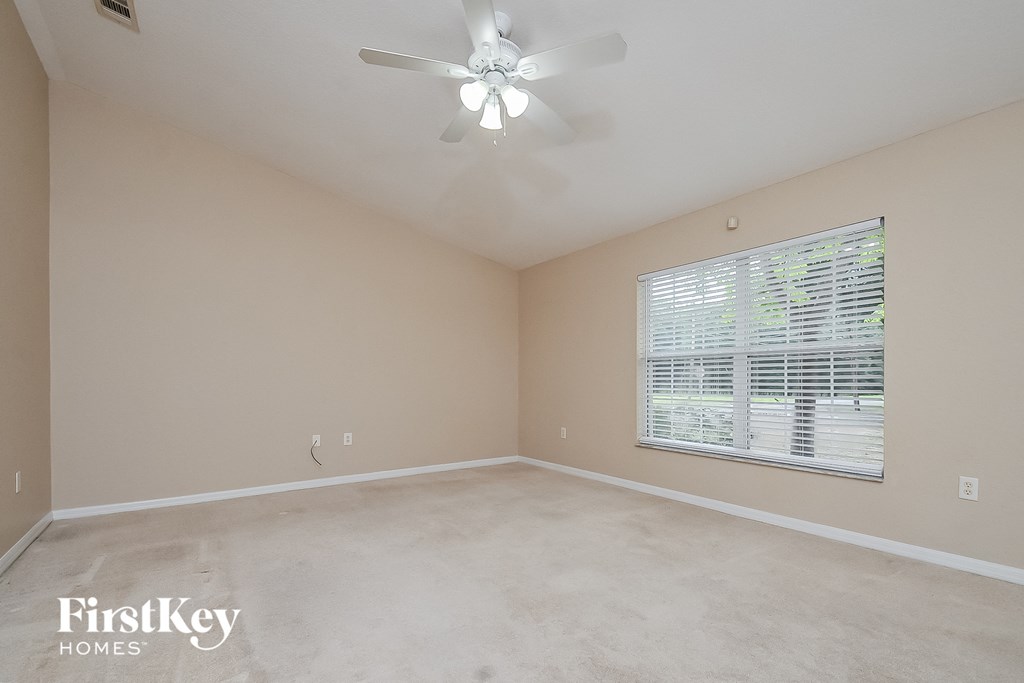 the master bedroom has a ceiling fan and a large window