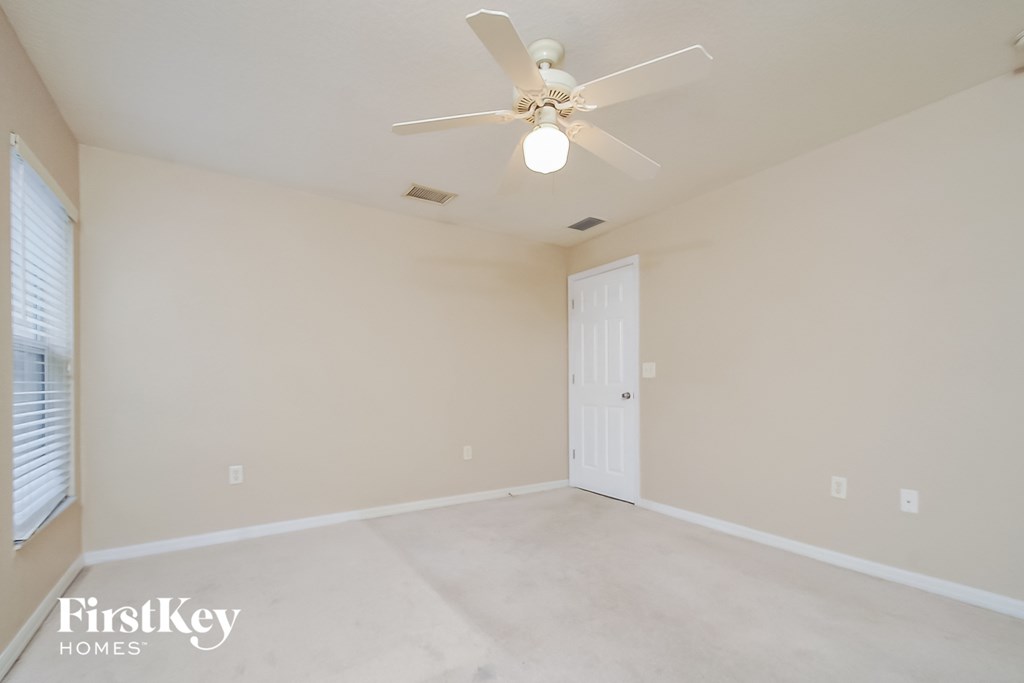 a empty living room with a ceiling fan and a white door