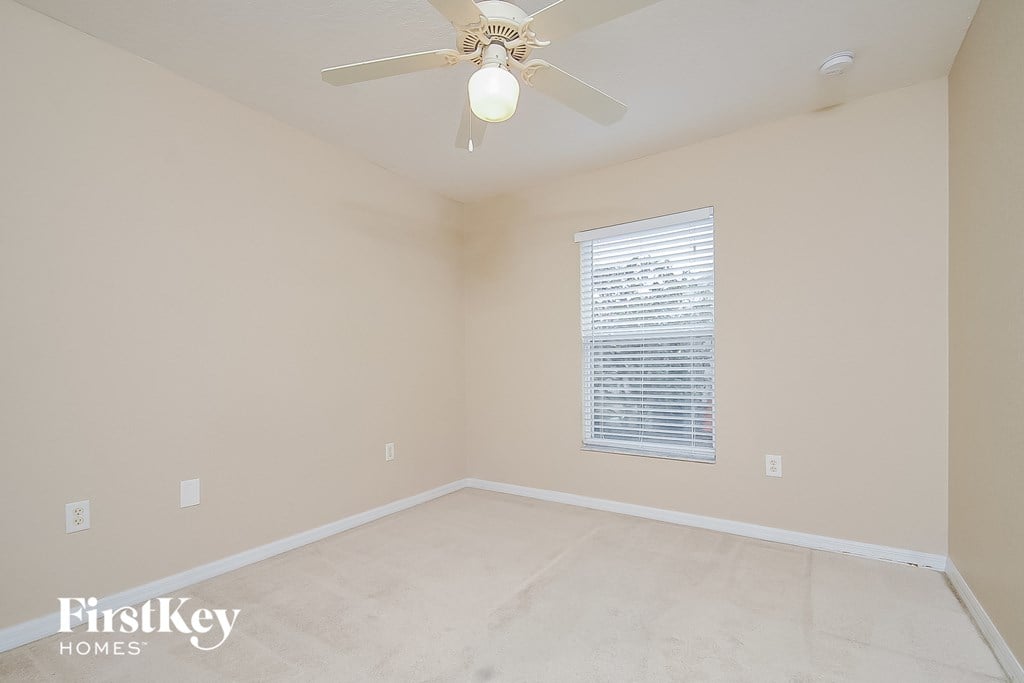 a empty room with a ceiling fan and a window