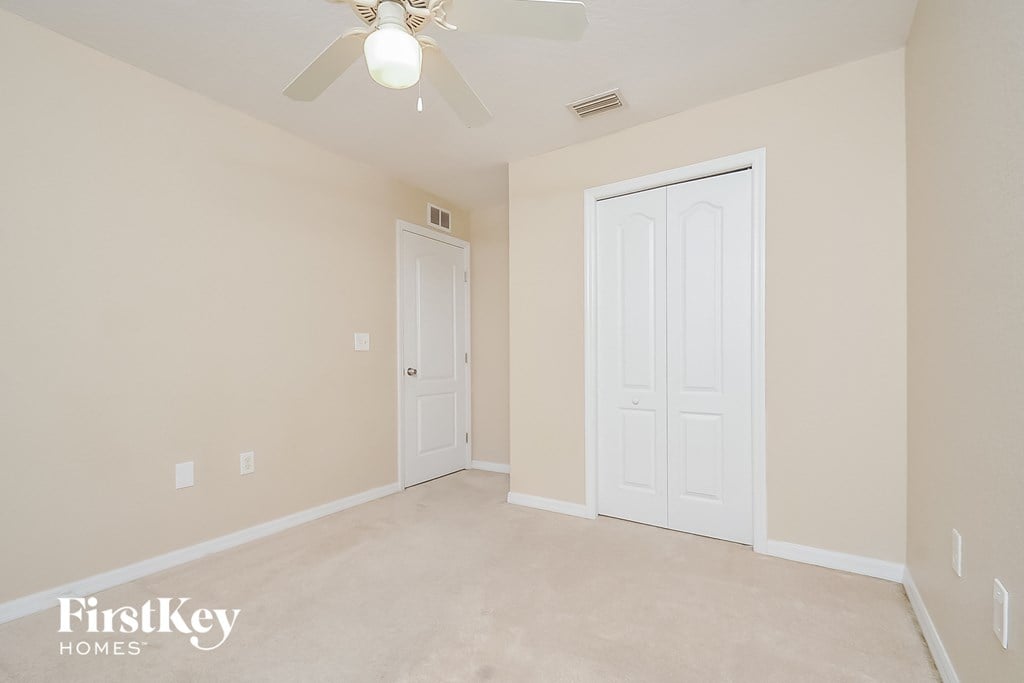 a bedroom with two doors and a ceiling fan