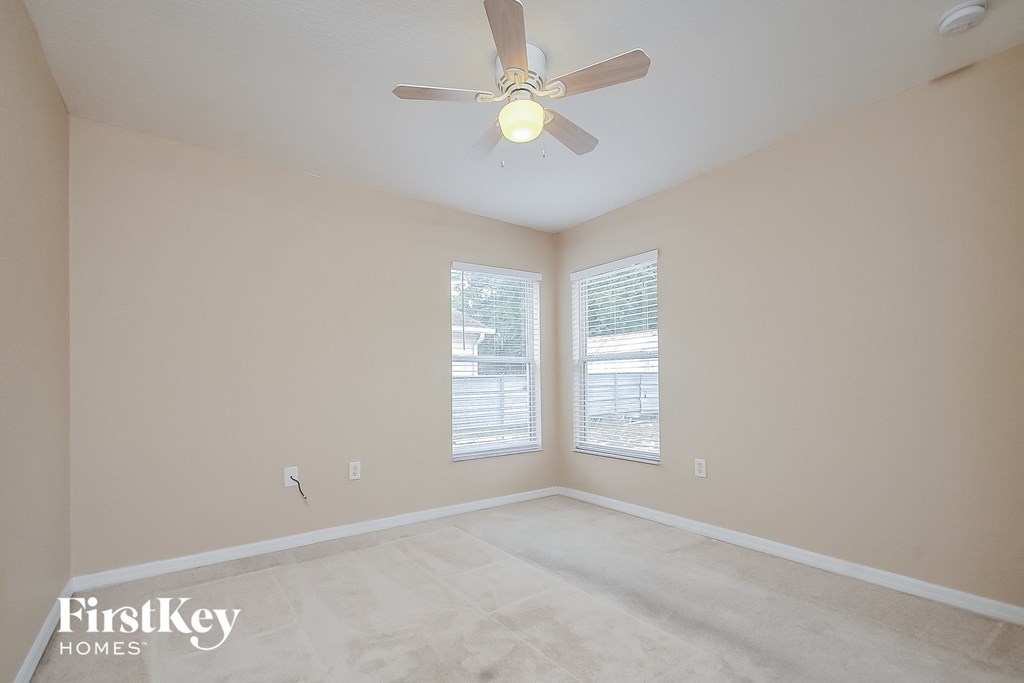 a bedroom with a ceiling fan and two windows