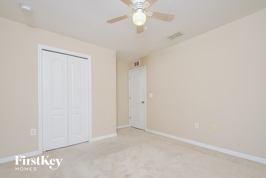 the spacious living room of an empty home with a ceiling fan