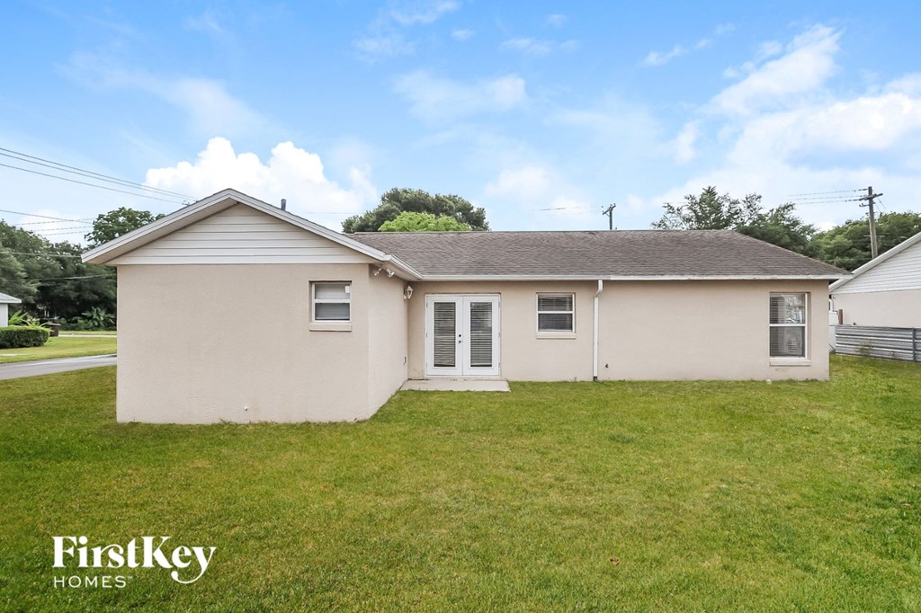 a small tan house with a grassy yard and a cloudy sky