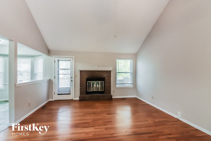 A large empty room with a fireplace and a window.