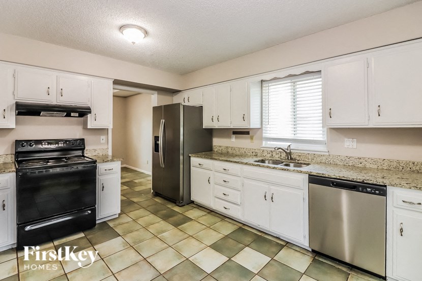 A kitchen with a black oven and white cabinets.