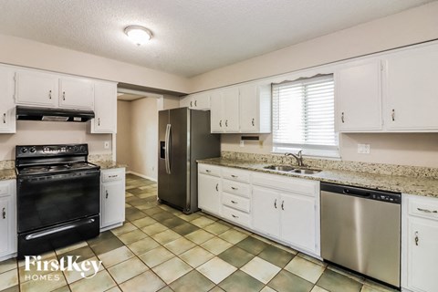 A kitchen with a black oven and white cabinets.