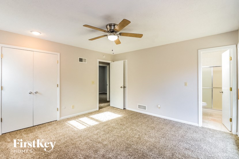 A spacious room with a ceiling fan and carpeted floor.