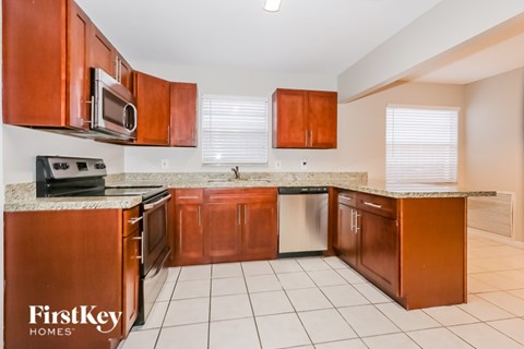 A kitchen with brown cabinets and a white tile floor.