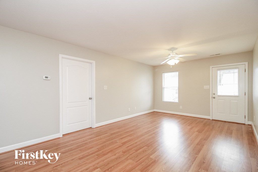 an empty living room with wood floors and a ceiling fan