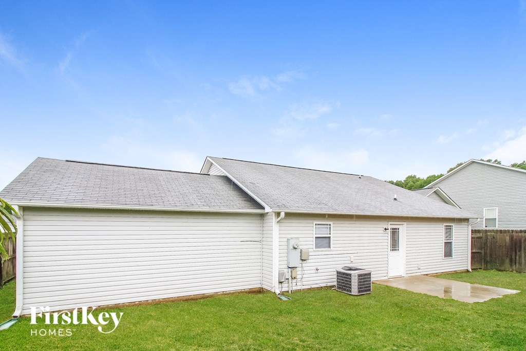 a small white house with a gray roof on a grass field