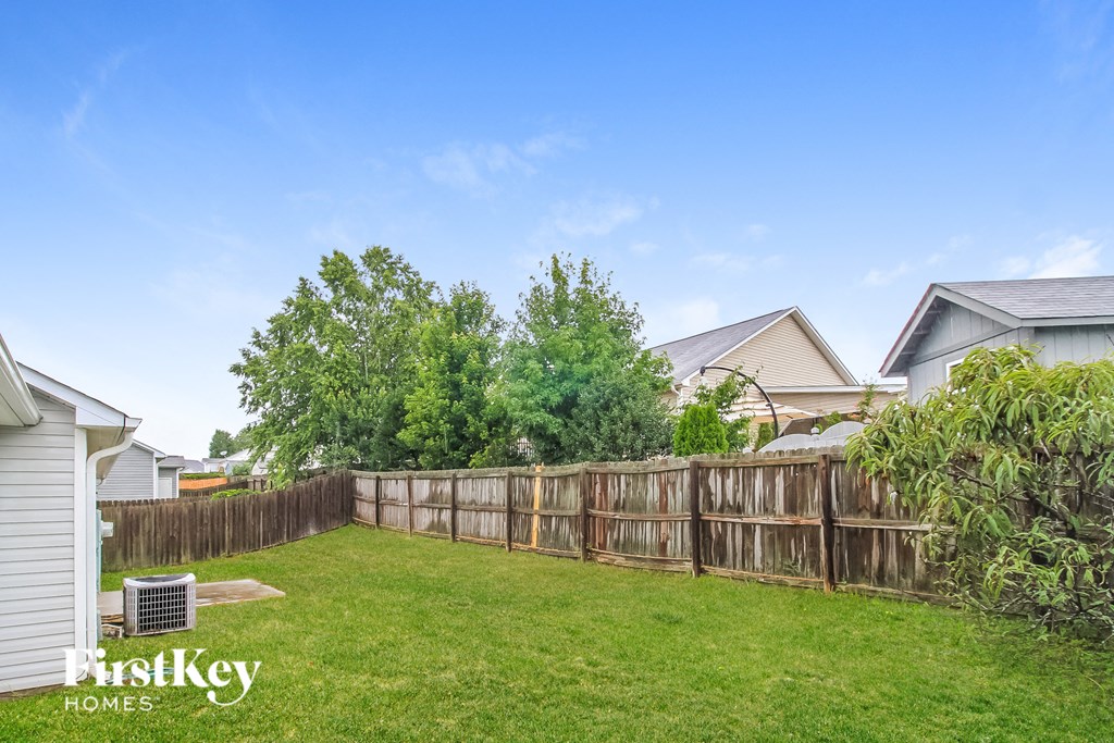 a backyard with a wooden fence and a green lawn