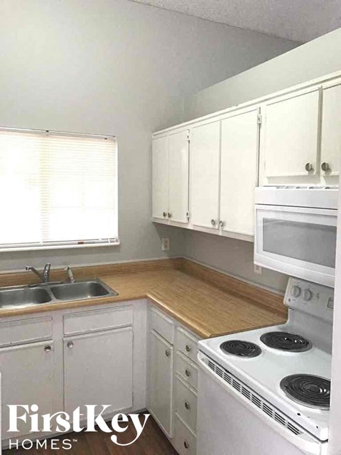 A kitchen with white appliances and cabinets.