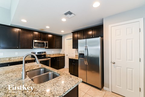 a kitchen with granite counter tops and stainless steel refrigerator