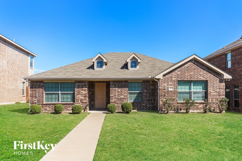 A brick house with a brown door and windows is for sale.