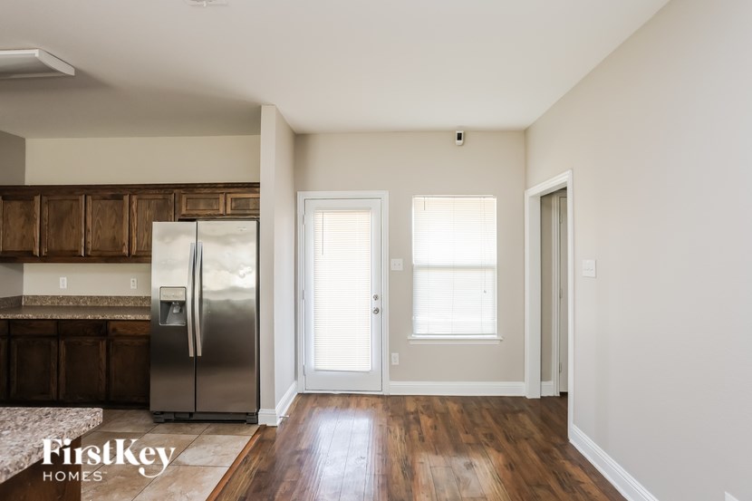 A kitchen with a refrigerator, cabinets, and a rug.