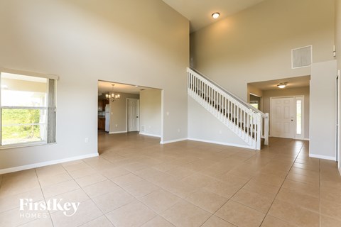 A spacious living room with a staircase leading to the upper floor.