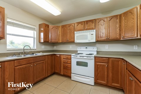 A kitchen with wooden cabinets and a white stove top oven.