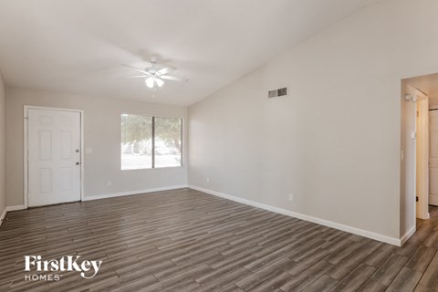 the spacious living room with wood flooring and a ceiling fan