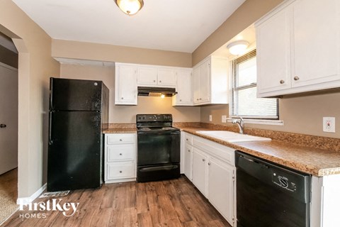 a kitchen with white cabinets and black appliances and a counter top