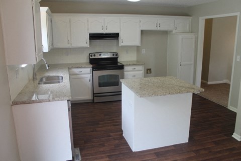 A kitchen with white cabinets and a granite counter.